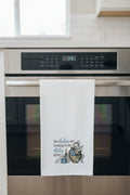 Kitchen towel with humorous design and text hanging on a rack.