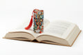 A rectangular decorative bookmark with a red tassel, featuring the text 'MAKING DIFFERENCE EVERY DAY' in colorful lettering over a pattern of fruits, books, and flowers, set against a solid orange background.